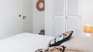 A bedroom with a bed, two pillows, a bedside lamp, a door, and a wall-mounted mirror. - Les Restanques Golfe Saint Tropez by Interhome (Grimaud)