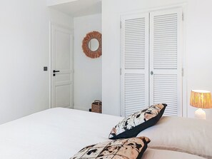 Une chambre à coucher avec un lit, deux oreillers, une lampe de chevet, une porte et un miroir fixé au mur.