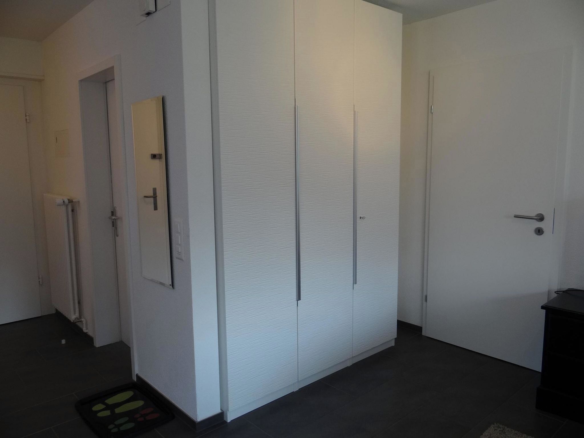 A hallway with a white wardrobe, a door, and a radiator.