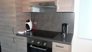 Una cucina moderna con mobili in legno, un piano di lavoro nero, forno a incasso e macchina per il caffè.