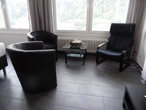 Una sala moderna con un sofá de cuero negro, un sillón a juego y una pequeña mesa de centro.