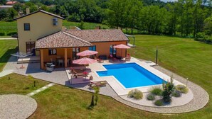 Ein zweistöckiges Haus mit Swimmingpool, Sitzgelegenheiten im Freien und einem gepflegten Rasen.