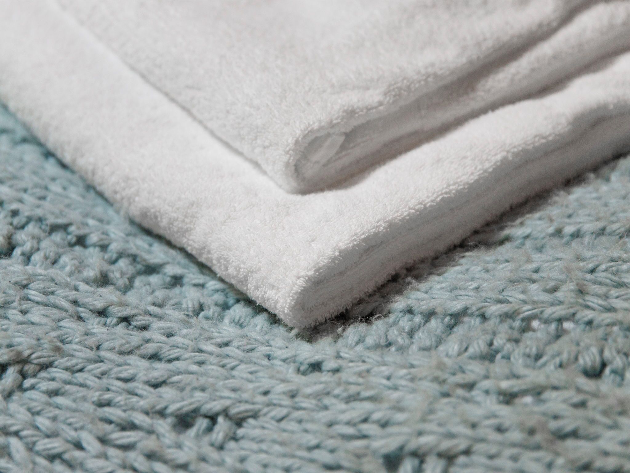 A folded white towel on a textured blue surface.