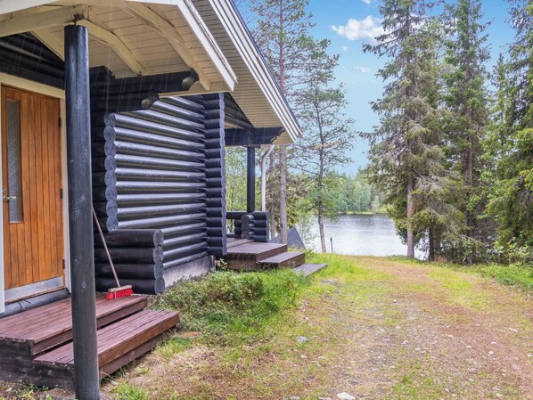 A log cabin with a porch and steps leading to a wooden door.