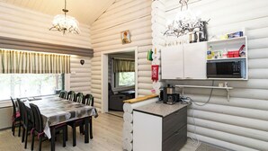 A log cabin interior with a dining area, kitchen, and a view of the outdoors.