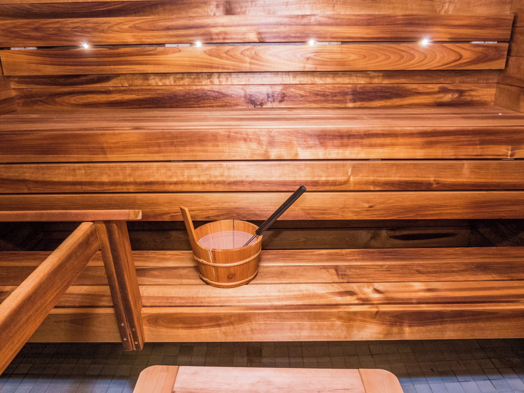 A wooden sauna bench with a wooden bucket and a long-handled ladle.