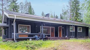 A log cabin with a porch, a bench, and a door.