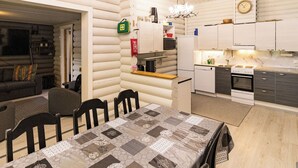 A log cabin interior with a dining area, kitchen, and living space.