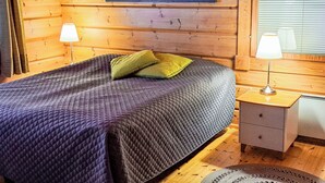 Une chambre rustique en bois, avec un lit, deux lampes de chevet et un tableau encadré au mur.