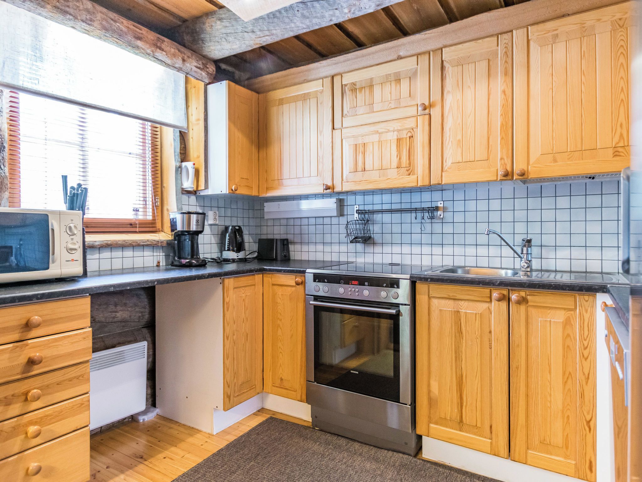 A kitchen with wooden cabinets, a built-in oven, a coffee maker, and a microwave.