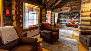 Ein Interieur einer Blockhütte mit Ledersofas, Holzboden und Kamin.