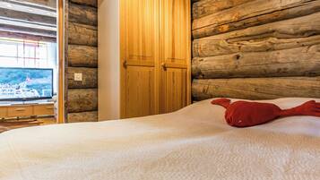 A room with a bed, a wooden wardrobe, and a window with a view of a boat.