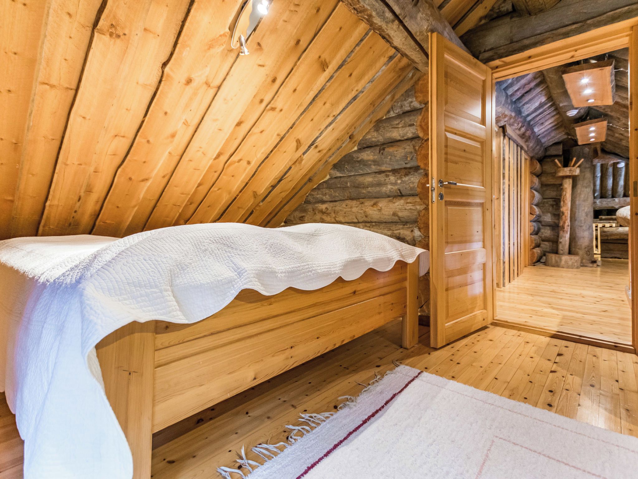 A wooden bunk bed with a white bedspread in a log cabin room.