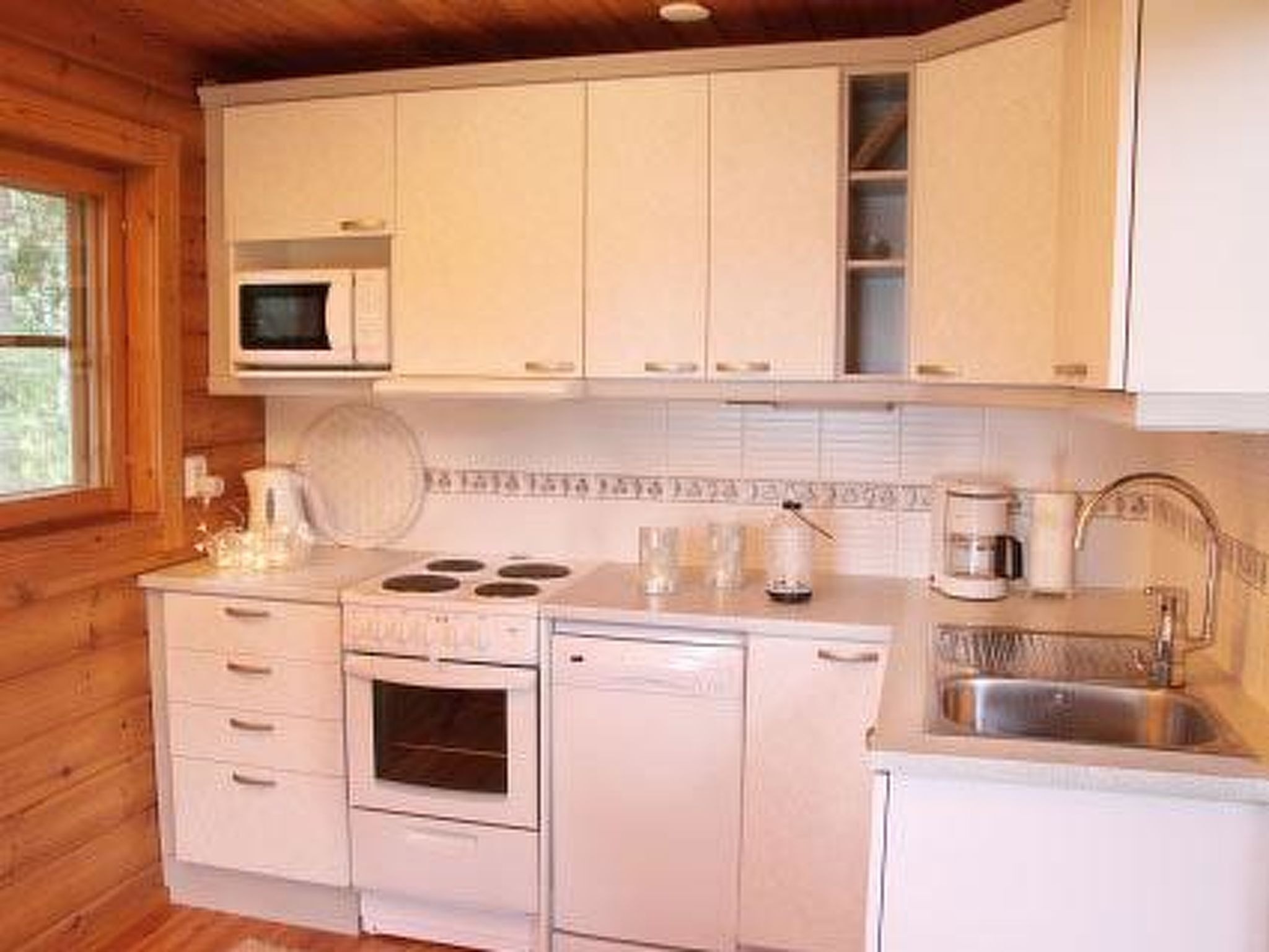A compact kitchen with white cabinetry, a microwave, a stove, and a sink.
