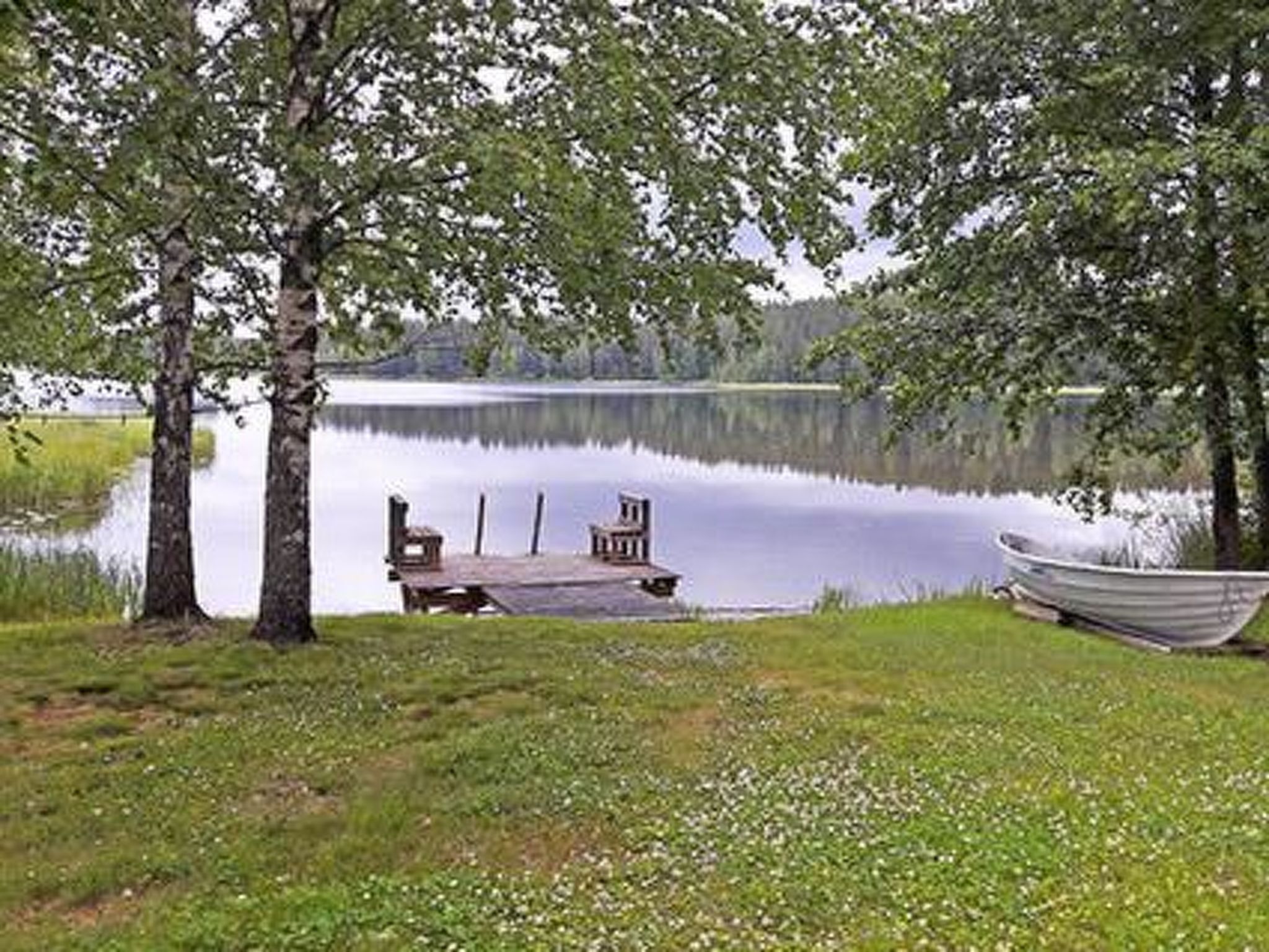 A lakeside dock with a boat, a bench, and a small table.
