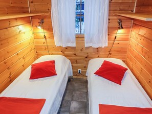 A cabin with two beds, each with a red pillow, and a window with white curtains. - Aslakit b by Interhome (Kittilä)