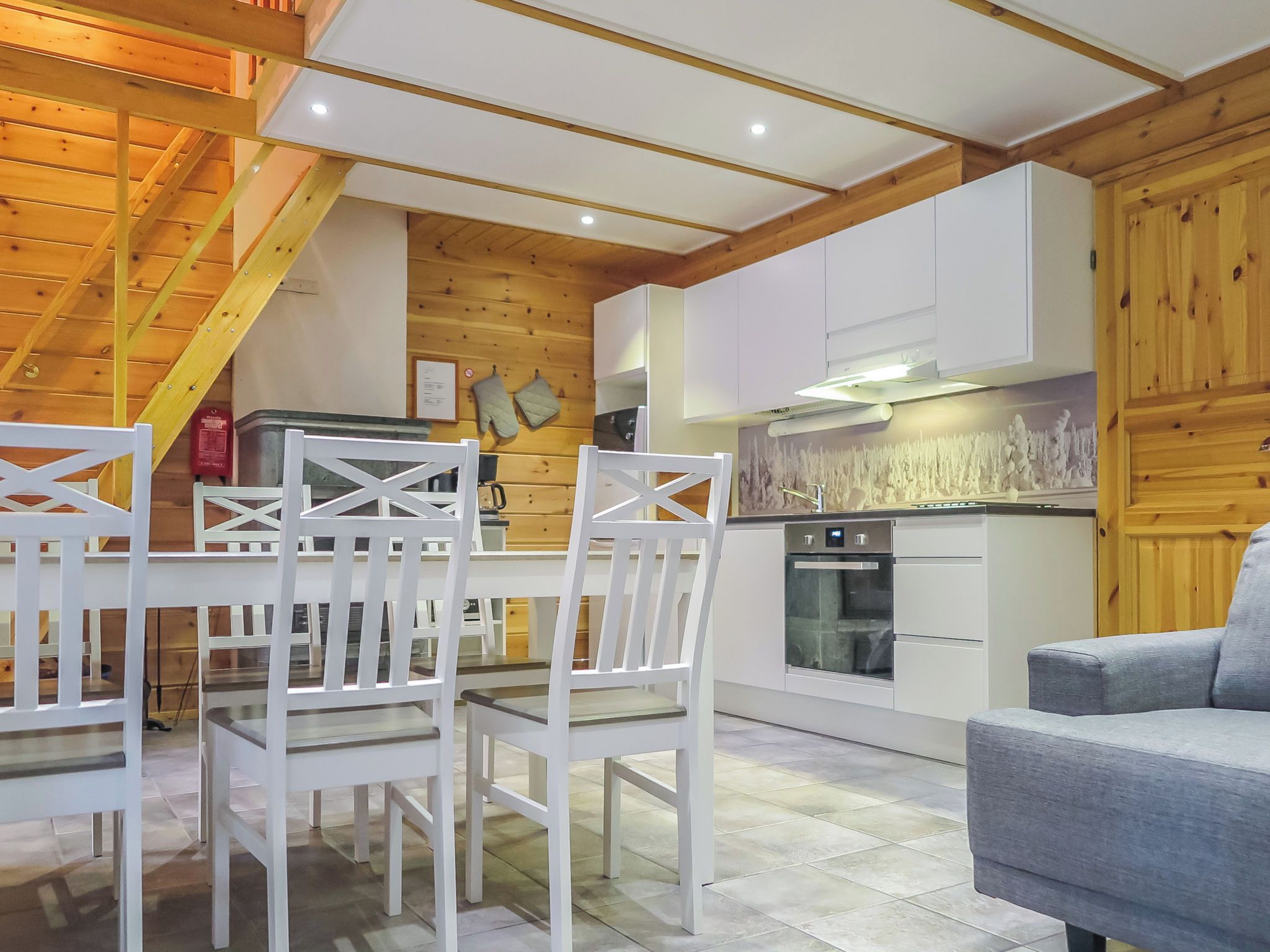 A modern kitchen with white cabinetry, a built-in oven, and a wooden ceiling.