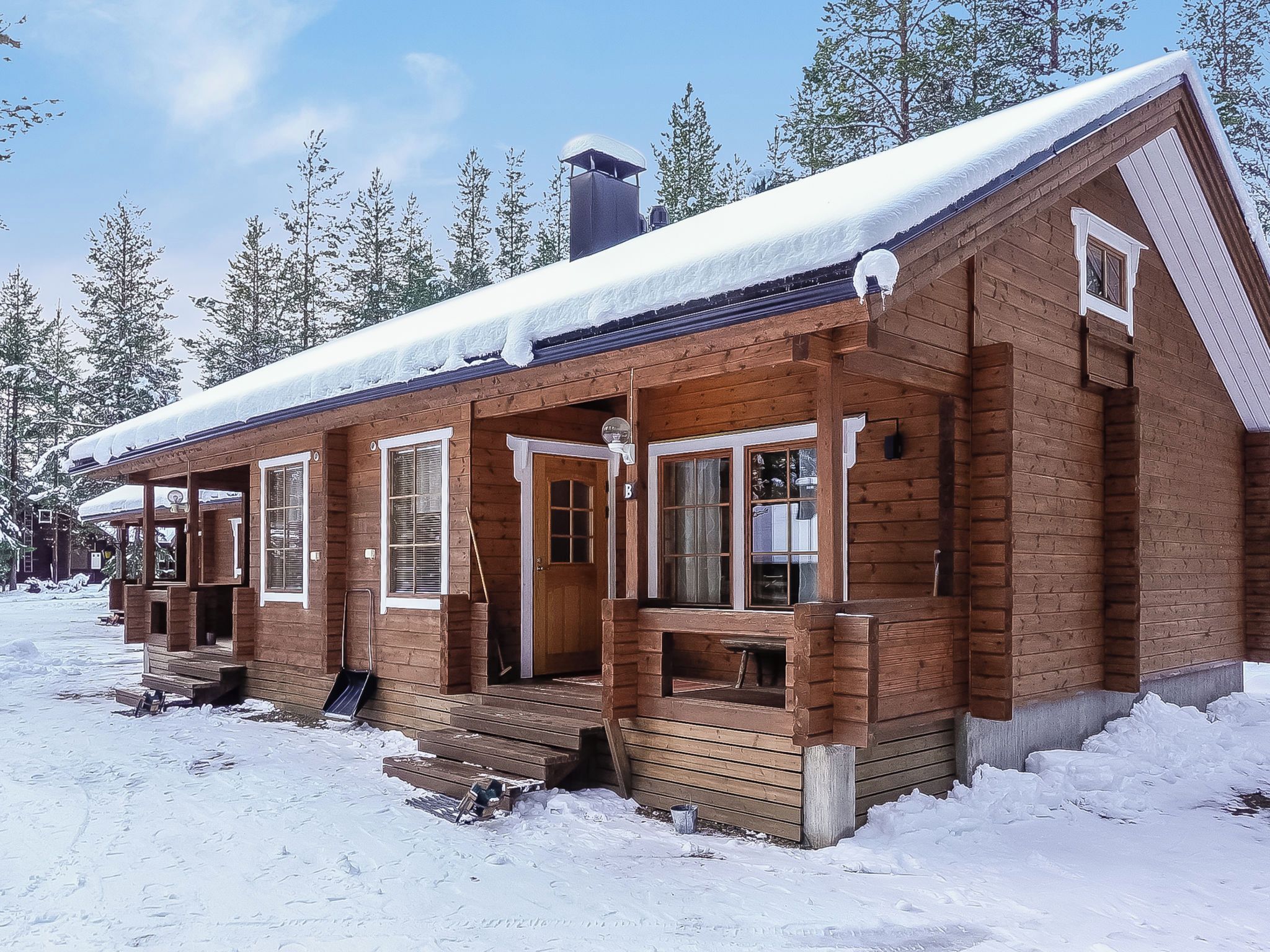 A wooden cabin with a porch, multiple windows, and a chimney.