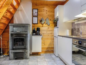 A kitchen with a stone fireplace, wooden wall paneling, and modern appliances. - Aslakit b by Interhome (Kittilä)