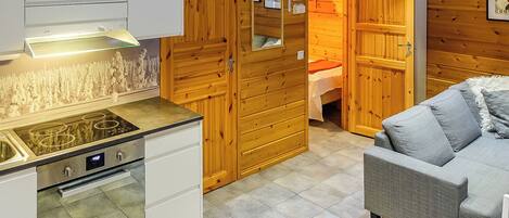 A compact kitchen with modern appliances, wooden walls, and a cozy seating area.