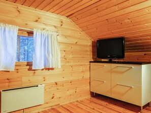 A cabin interior with wooden walls, a window with curtains, a television on a cabinet, and a radiator. - Aslakit b by Interhome (Kittilä)