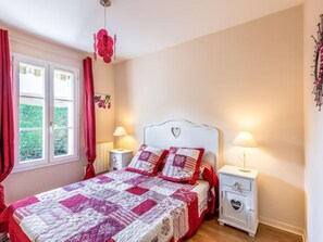 Ein Schlafzimmer mit einem Bett, zwei Nachttischen, einem Fenster mit Vorhängen und einer Wanddekoration.