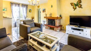Uma sala de estar com lareira, televisão e área de jantar com mesa e cadeiras.
