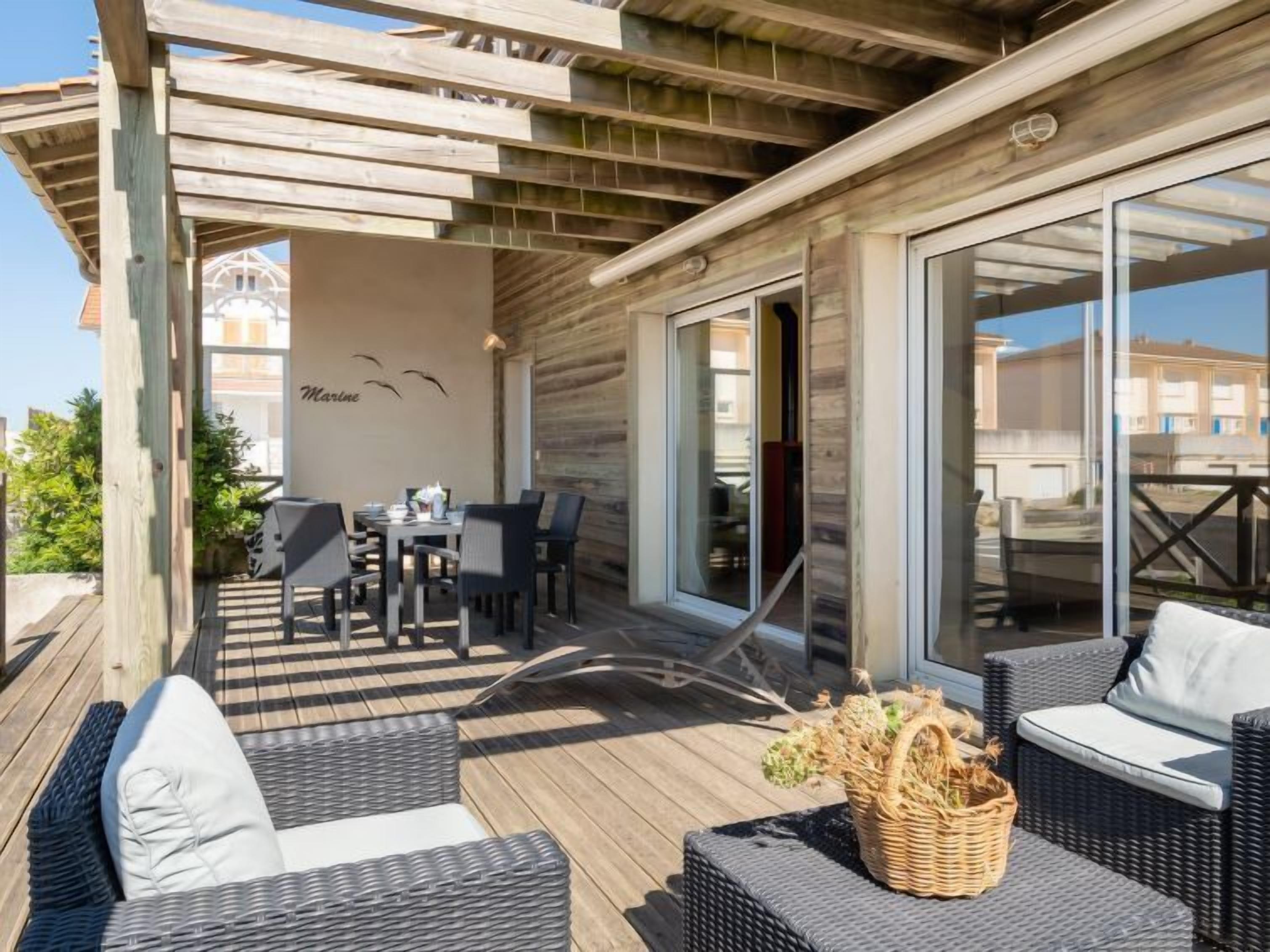 An outdoor patio with wicker furniture, a dining table, and a glass door leading to an interior space.