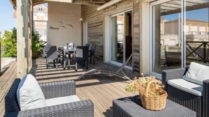 An outdoor patio with wicker furniture, a dining table, and a glass door leading to an interior space.