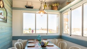 A dining area with a table set for four, large windows, and a view of the beach.