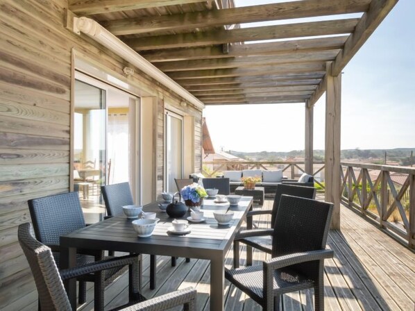 Eine Holzterrasse mit Essbereich, umgeben von Korbstühlen.
