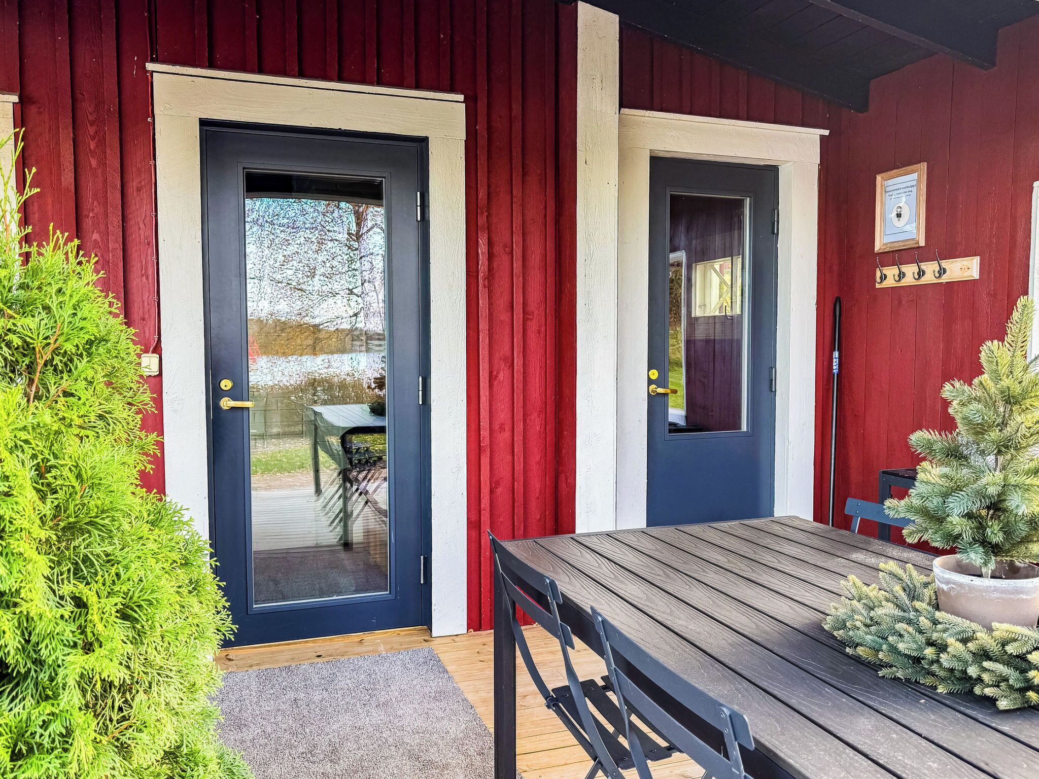 A wooden deck with a table and chairs, a door, and a small Christmas tree.