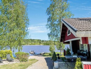 Una cabaña junto al lago con terraza, mobiliario exterior y vistas al lago.