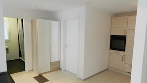 A modern, well-lit room with a tiled floor, a built-in oven, and a wardrobe.
