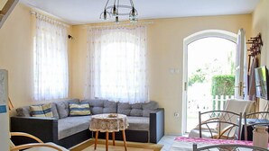 A living room with a sofa, a small round table, a rocking chair, and a dining area with a table and chairs. - Vacation home Welle by Interhome (Balatonmariafurdo)