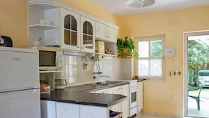 A kitchen with white cabinets, a microwave, and a sink. There is a window with a view of greenery outside. - Vacation home Welle by Interhome (Balatonmariafurdo)