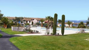 A residential area with a swimming pool, well-maintained lawns, and houses with Mediterranean architecture. - Le Golf de Roquebrune by Interhome (Roquebrune sur Argens)