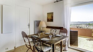 A dining area with a table set for four, a lamp, and a view of the outdoors. - Le Golf de Roquebrune by Interhome (Roquebrune sur Argens)