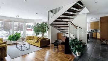 Ein modernes Wohnzimmer mit Treppe, Holzboden und großen Fenstern.