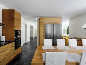 Una cocina moderna con una isla central, armarios de madera y un refrigerador de acero inoxidable.