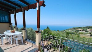 Una terraza con mesa y sillas, vistas al mar y un jardín.
