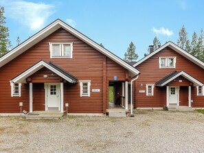 A two-story wooden cabin with a central entrance and individual doors for each unit.