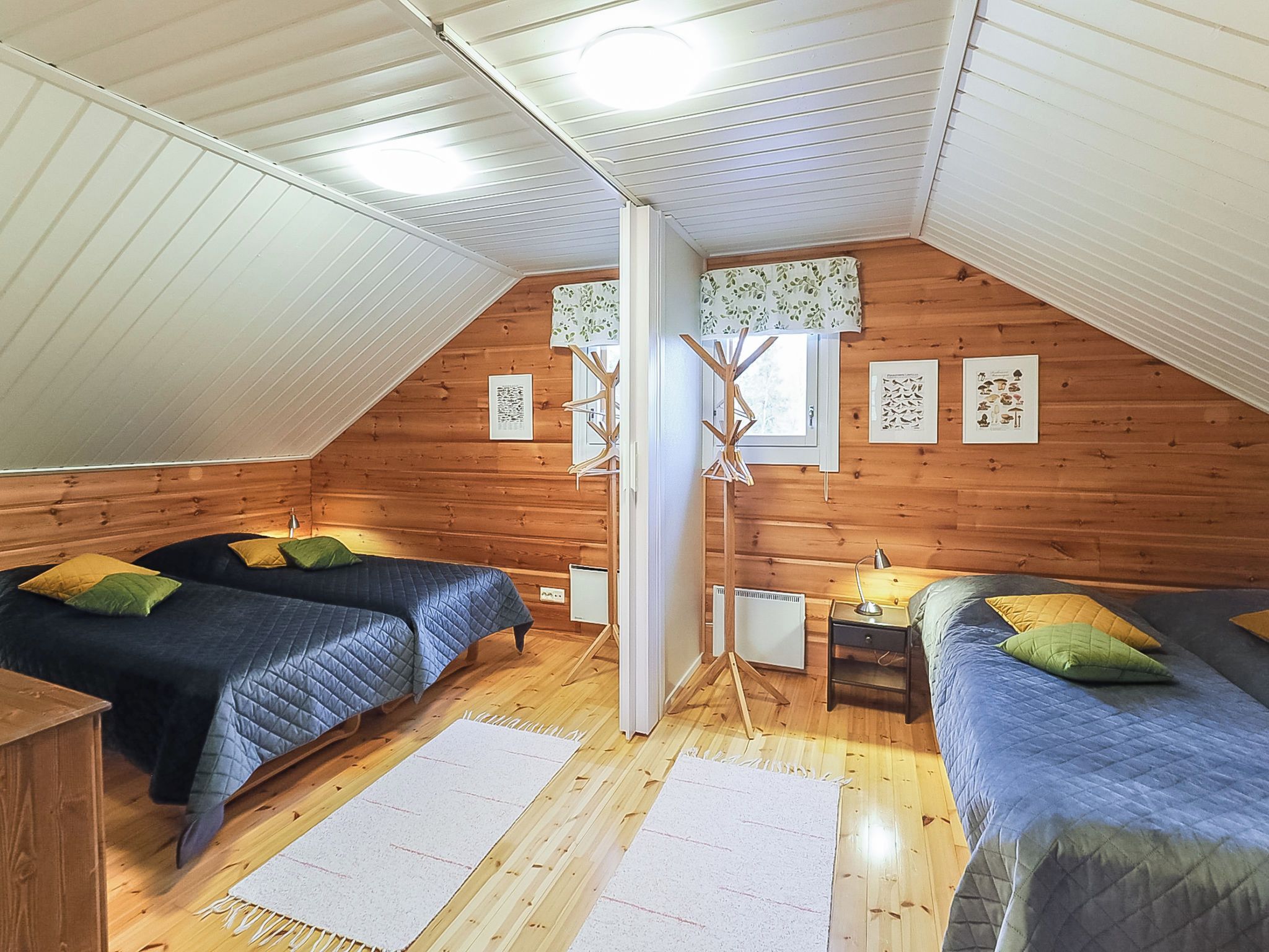 Un dormitorio acogedor en el ático con dos camas, piso de madera y techo inclinado.