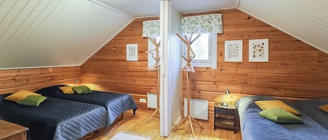 Un dormitorio acogedor en el ático con dos camas, piso de madera y techo inclinado.