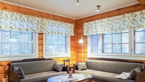 A cozy room with two sofas facing each other, a small round table, and large windows with curtains.