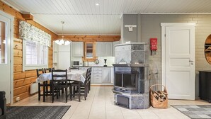 A cozy cabin interior with a dining area, kitchen, and fireplace.