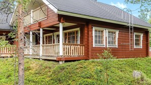 A two-story wooden house with a balcony, a chimney, and a porch.