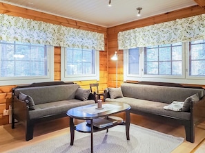 Ein gemütliches Zimmer mit zwei Sofas, einem kleinen Tisch und einer Lampe.
