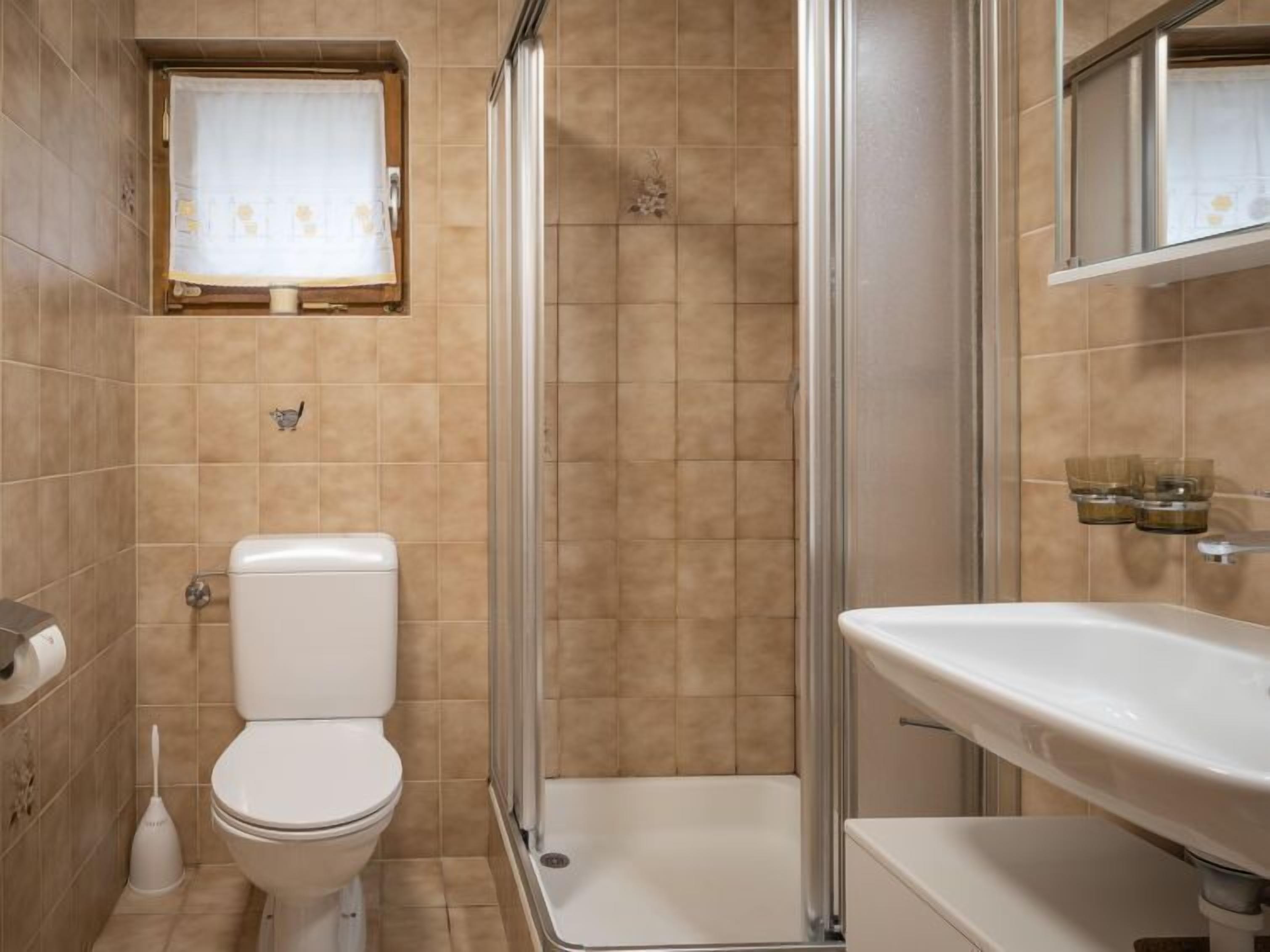 Een badkamer met toilet, douche en wastafel.