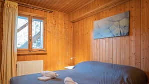 A wooden-paneled room with a bed, a window, and a painting on the wall. - Le Tzanton by Interhome (Ovronnaz)